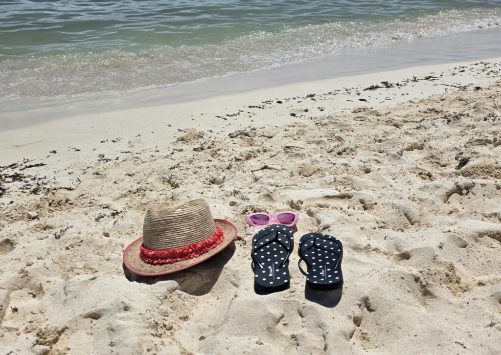 Kapelusz, okulary przeciwsłoneczne i klapki na piaszczystej plaży w Hiszpanii