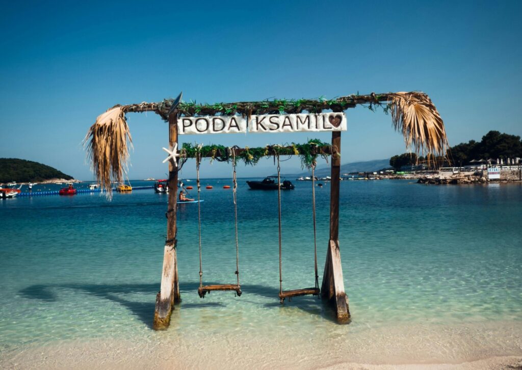 Drewniana huśtawka wodna na plaży Poda Ksamil z widokiem na turkusowe morze w Albanii