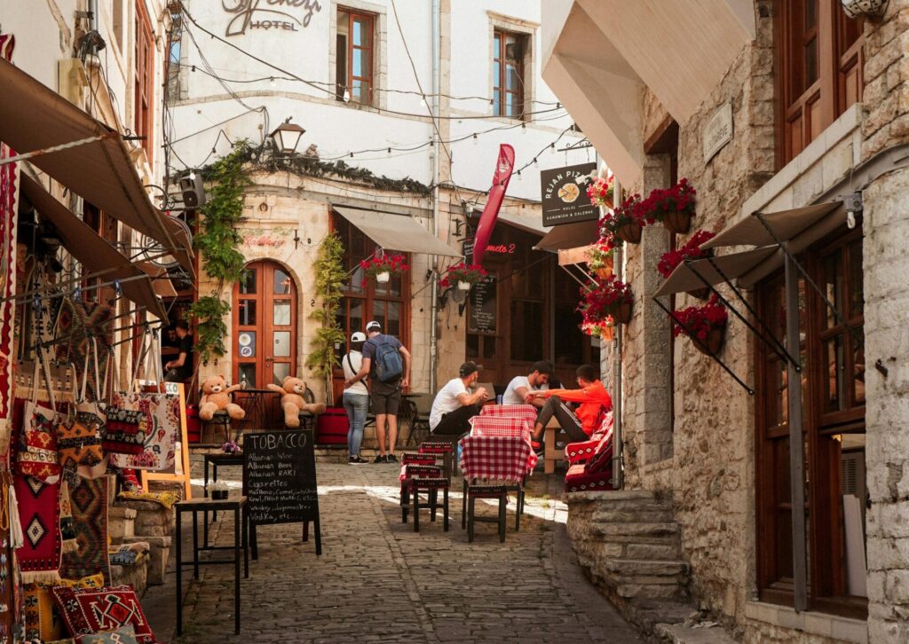 Kamienna uliczka Starego Bazaru w Gjirokastrze z kawiarnianymi stolikami i pamiątkami w Albanii