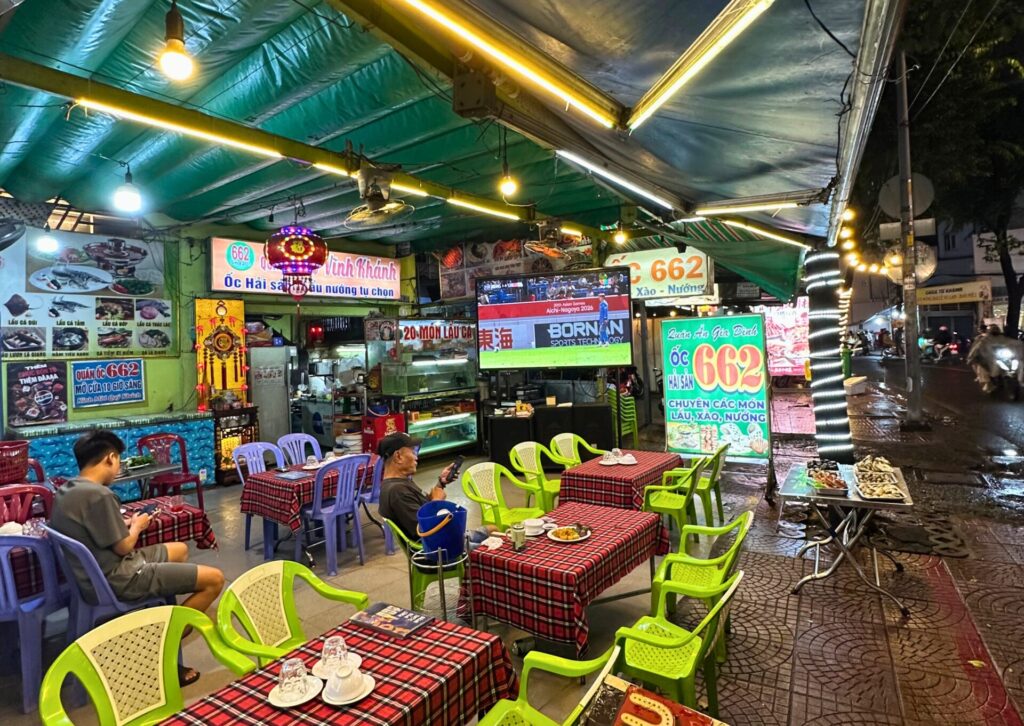 Tradycyjny wietnamski bar uliczny serwujący lokalne dania i owoce morza w nocy w Ho Chi Minh City