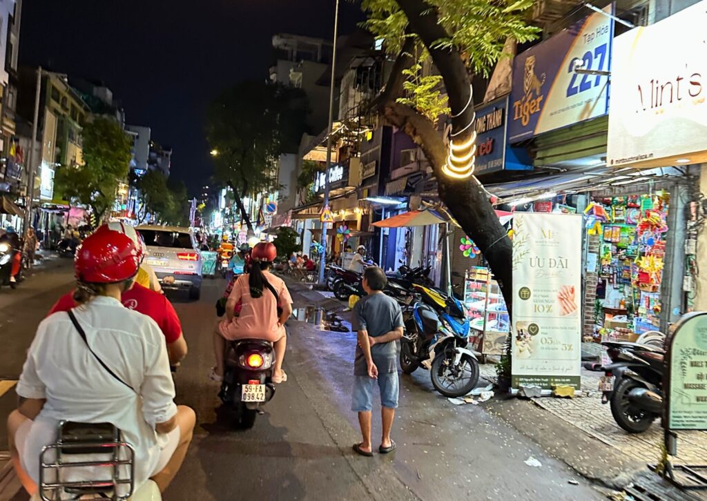 Nocny widok na przejeżdżające skutery i tętniącą życiem ulicę w Ho Chi Minh City