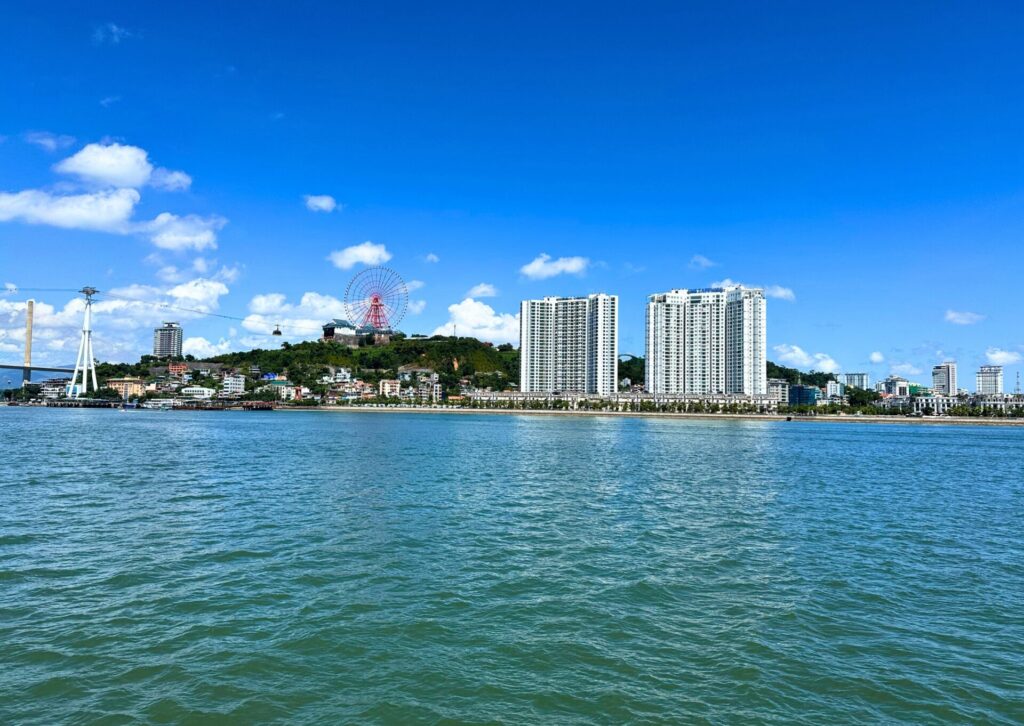 Widok z pokładu statku na nadmorskie miasto Ha Long i park rozrywki na wzgórzu – punkt startowy rejsu po zatoce Ha Long